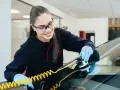 Une technicienne répare une fissure sur un pare-brise avec un équipement spécialisé. Elle sait exactement fissure pare brise que faire.