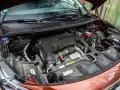 Vue rapprochée du moteur d'une voiture, prêt pour un nettoyage. On voit le bloc moteur, la batterie et divers composants.