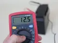 Multimètre affichant 12.5V, indiquant une batterie déchargée ou morte.