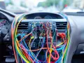 Tableau de bord d'une voiture envahi par un enchevêtrement de fils colorés, un vrai casse-tête pour le **code couleur fil haut parleur**.