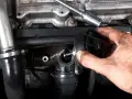 Main d'un mécanicien tenant une pièce de vanne EGR. Faut-il reprogrammer après changement vanne egr ? Question technique sur le moteur.