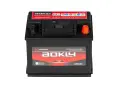 Une batterie AOKLY noire, 12V 55Ah, avec des étiquettes rouges et blanches indiquant "Maintenance Free Battery" et des symboles d'attention.