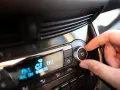 Main de conducteur ajustant le bouton "MAX A/C" sur le tableau de bord. Faut-il laisser la climatisation voiture en permanence ?