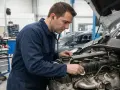 Mécanicien écoutant un moteur qui claque, suspectant un manque d'huile. Diagnostic en cours dans un atelier.