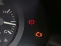 Tableau de bord d'une voiture avec le voyant moteur allumé, signalant un problème. Le voyant d'alerte de freinage est également visible.