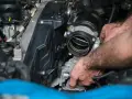 Mains d'un mécanicien travaillant sur un moteur, possiblement pour diagnostiquer un débitmètre d'air défectueux symptôme.