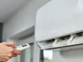 Main tenant utilise la télécommande pour régler la climatisation. Un problème climatisation voiture ? Ici, c'est pour une maison.