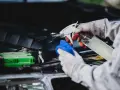 Gants et chiffon bleu pour comment nettoyer un moteur de voiture plein d'huile. Vaporisation d'un produit sur le moteur.