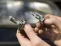 Deux ampoules de feu de croisement voiture sont tenues dans des mains. L'une est déjà retirée, l'autre est sur le point de l'être.