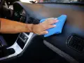 Main d'homme nettoyant le tableau de bord d'une voiture avec un chiffon bleu. Un nettoyant plastique voiture fait maison pour un intérieur impeccable.