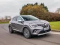 Une Renault Captur 2 grise roule sur une route sinueuse, prête pour son programme d'entretien.
