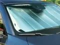 Pare-soleil argenté installé sur un pare-brise de voiture. Facile à mettre, il protège de la chaleur.