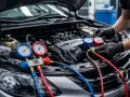 Un mécanicien vérifie la pression du système de climatisation d'une voiture avec des manomètres. La durée de recharge clim est cruciale pour son bon fonctionnement.