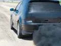 Voiture noire émettant une épaisse fumée noire sans perte de puissance, sur une piste.