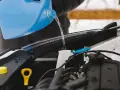 Personne verse du liquide dans le réservoir pour fabriquer lave glace. Le liquide coule d'une grande bouteille bleue vers le compartiment moteur.
