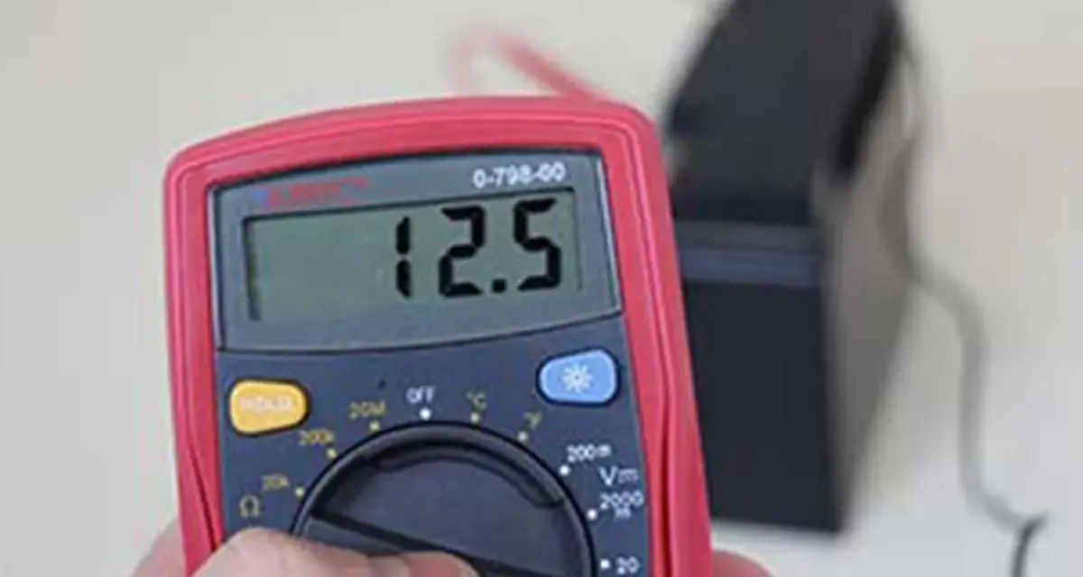 Multimètre affichant 12.5V, indiquant une batterie déchargée ou morte.