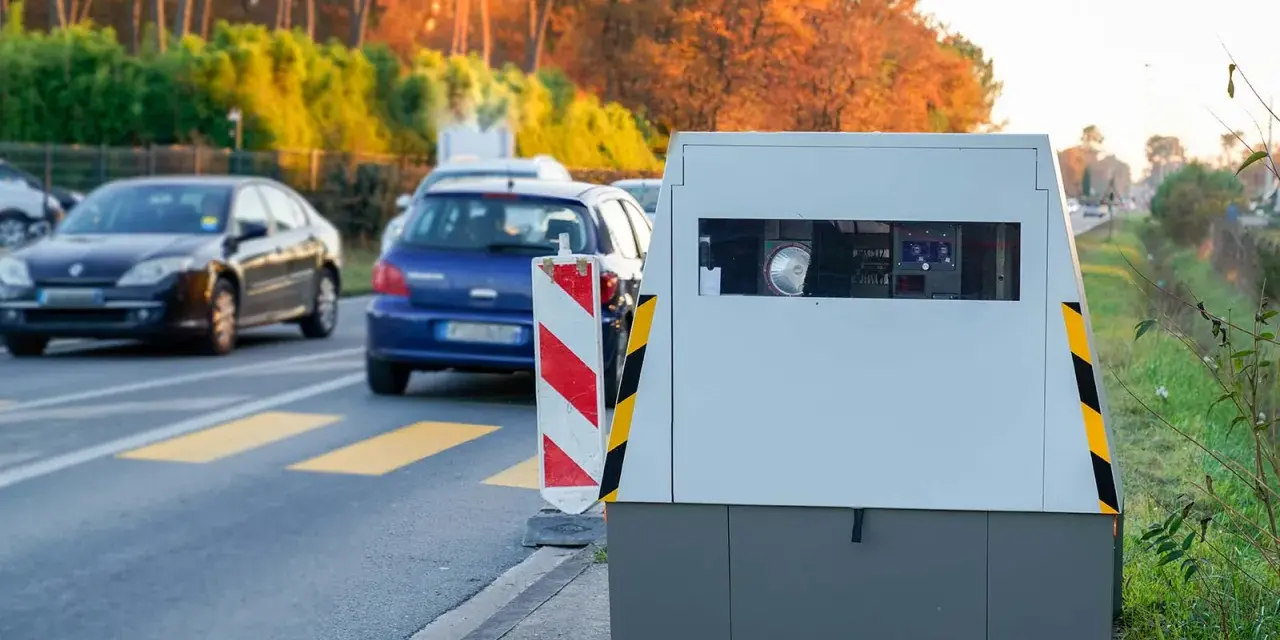 Un radar mobile de voiture surveille la route. Des voitures passent devant, dans un décor automnal.