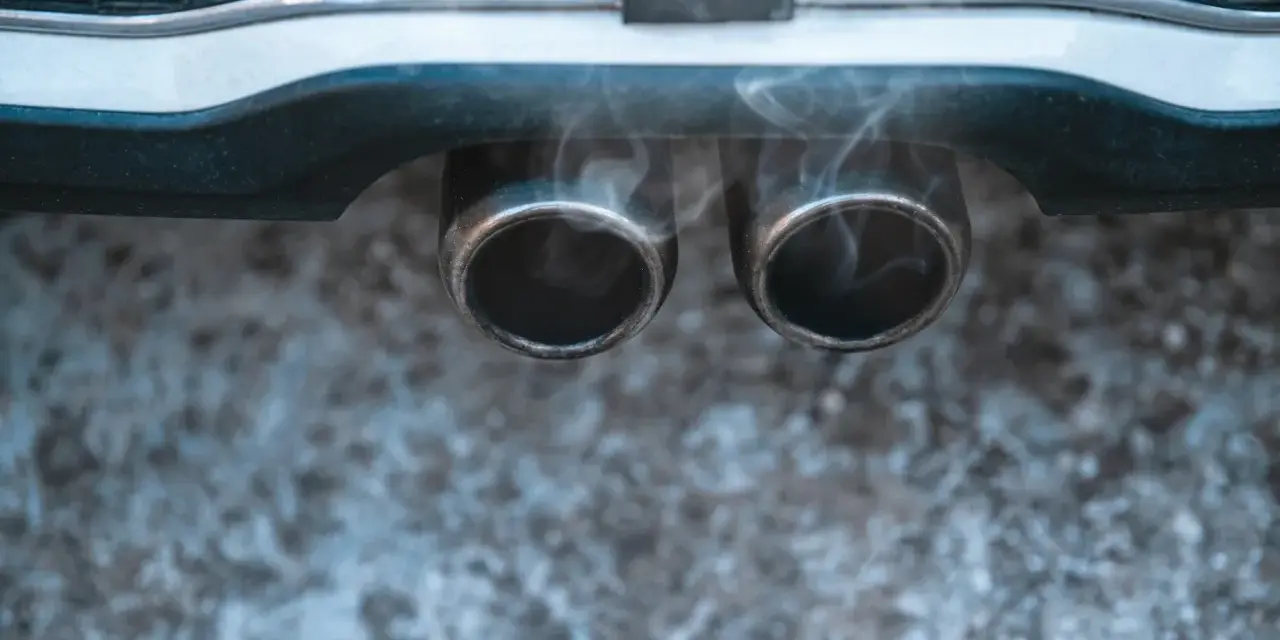 Vapeur d'eau sortant des deux pots d'échappement d'une voiture, suggérant un démarrage par temps froid.