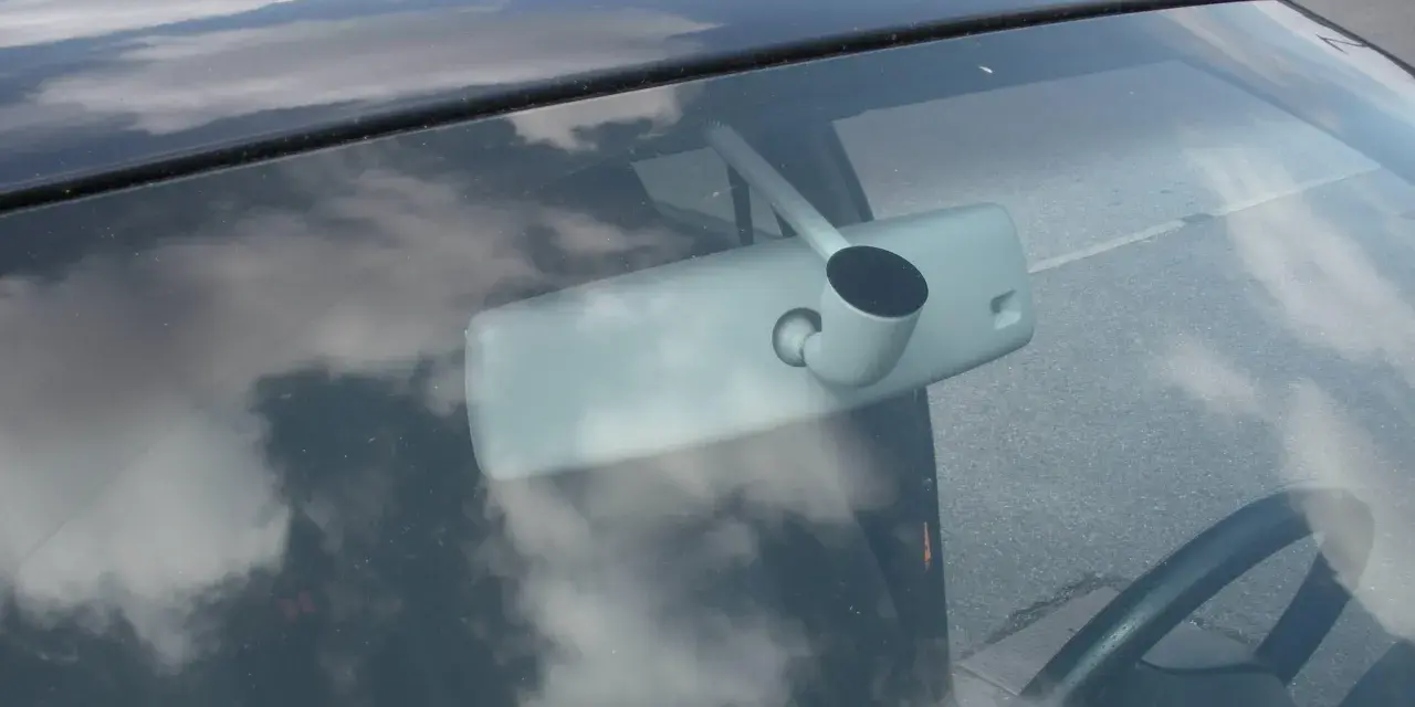 Vue intérieure d'une voiture, montrant le rétroviseur et le volant. Apprenez comment emboîter un rétroviseur intérieur pour une installation facile.