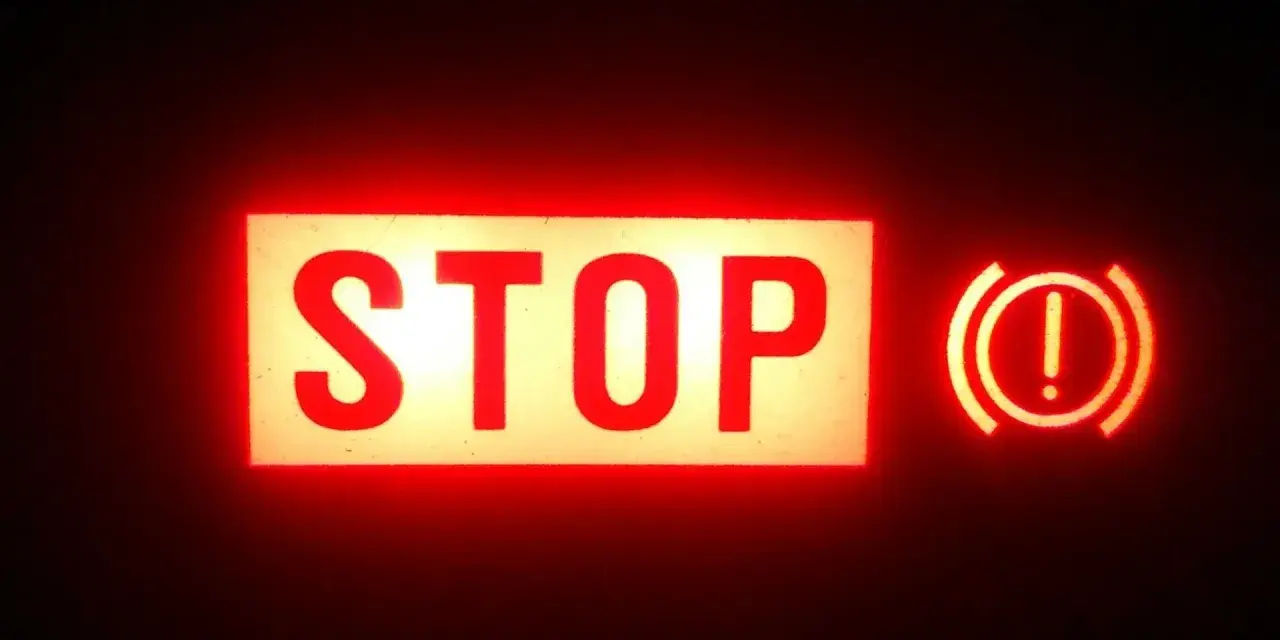 Voyant STOP et symbole de frein à main allumés en rouge. Vérifiez le niveau du liquide de frein.