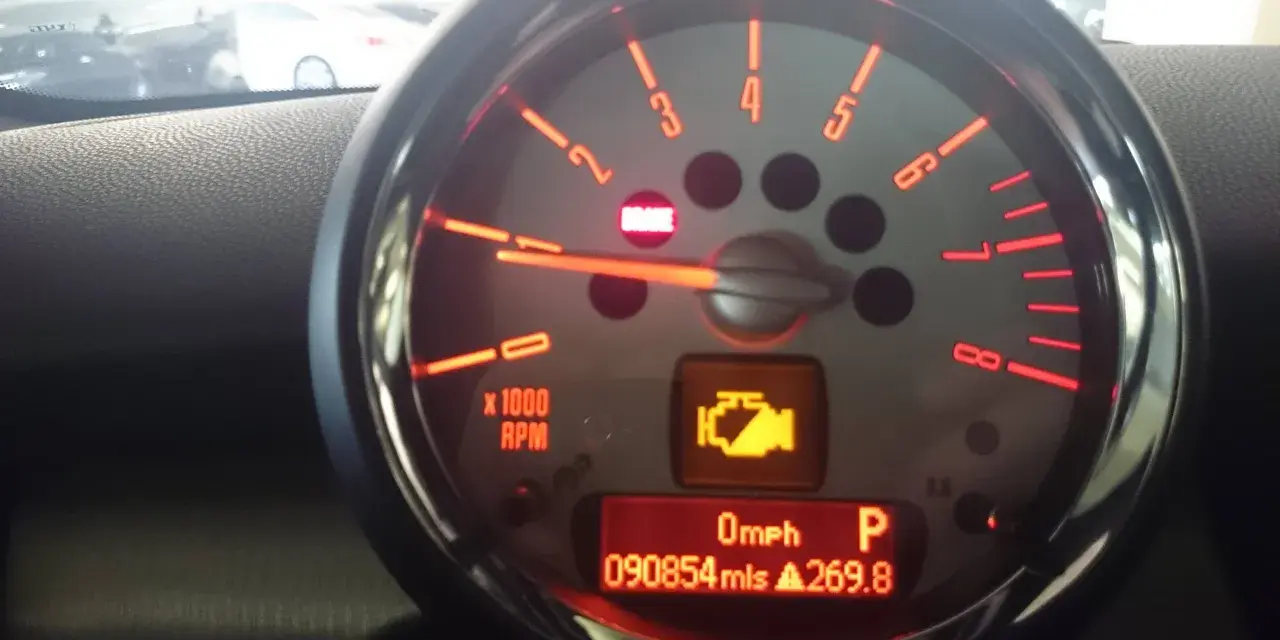Tableau de bord d'une voiture avec voyant moteur allumé, indiquant un dysfonctionnement du système de contrôle des gaz d'échappement. Kilométrage : 90854 miles.