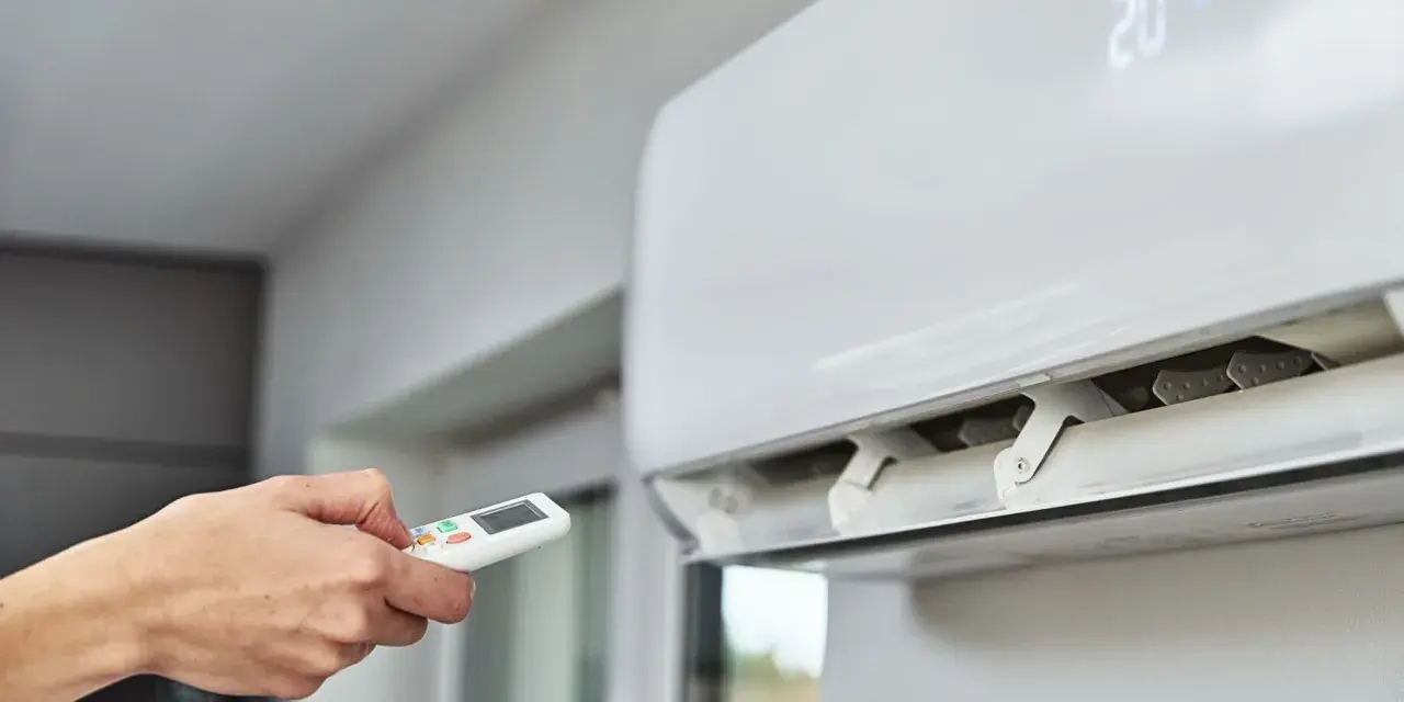 Main tenant utilise la télécommande pour régler la climatisation. Un problème climatisation voiture ? Ici, c'est pour une maison.