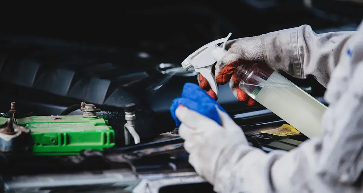 Gants et chiffon bleu pour comment nettoyer un moteur de voiture plein d'huile. Vaporisation d'un produit sur le moteur.