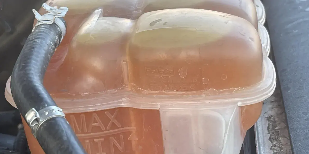 Le réservoir de liquide de refroidissement est plein, indiquant trop de liquide de refroidissement. Les marques MAX et MIN sont visibles.