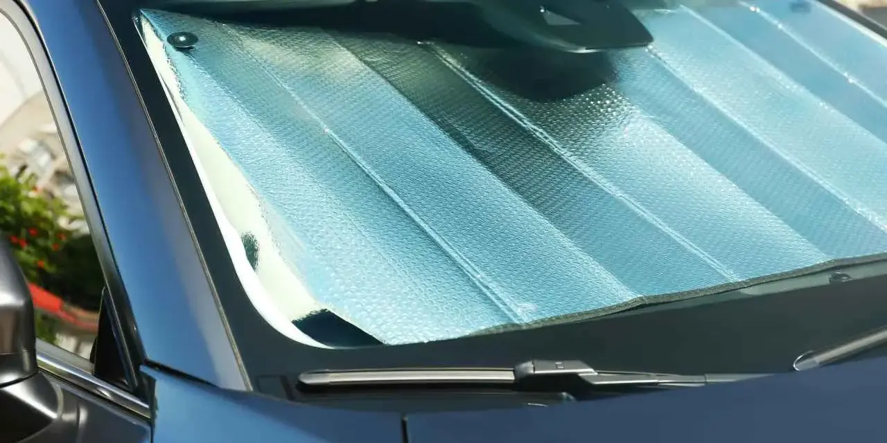 Pare-soleil argenté installé sur un pare-brise de voiture. Facile à mettre, il protège de la chaleur.