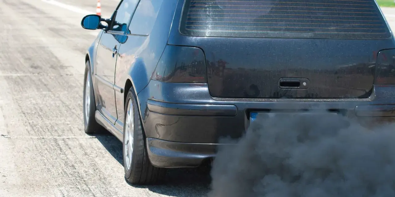 Voiture noire émettant une épaisse fumée noire sans perte de puissance, sur une piste.