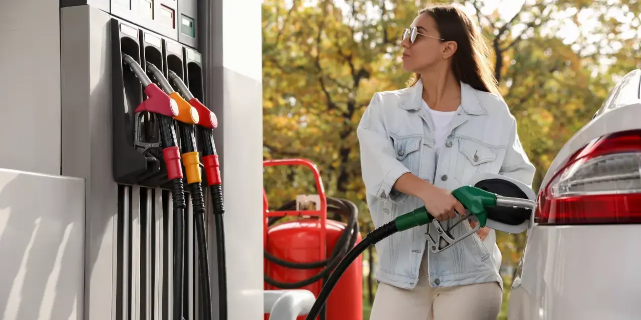 Femme faisant le plein d'essence, inquiète des symptômes de mauvais carburant voiture.
