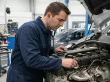 Mécanicien écoutant un moteur qui claque, suspectant un manque d'huile. Diagnostic en cours dans un atelier.
