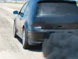 Voiture noire émettant une épaisse fumée noire sans perte de puissance, sur une piste.