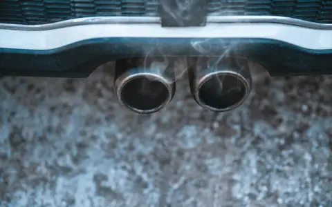Vapeur d'eau sortant des deux pots d'échappement d'une voiture, suggérant un démarrage par temps froid.