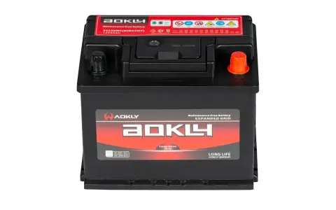 Une batterie AOKLY noire, 12V 55Ah, avec des étiquettes rouges et blanches indiquant "Maintenance Free Battery" et des symboles d'attention.