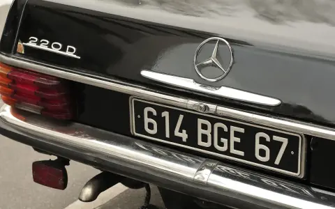 Arrière d'une Mercedes 220D noire. La plaque d'immatriculation "614 BGE 67" est visible. Pour savoir les chevaux de ma voiture, il faut regarder la carte grise.