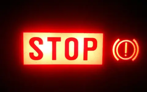 Voyant STOP et symbole de frein à main allumés en rouge. Vérifiez le niveau du liquide de frein.