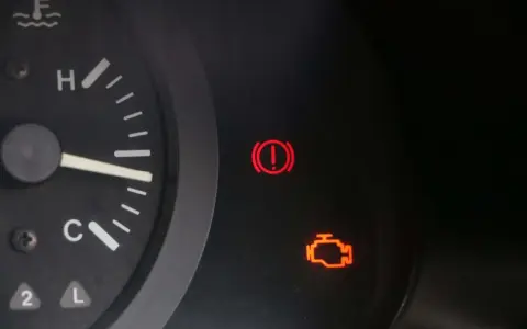 Tableau de bord d'une voiture avec le voyant moteur allumé, signalant un problème. Le voyant d'alerte de freinage est également visible.