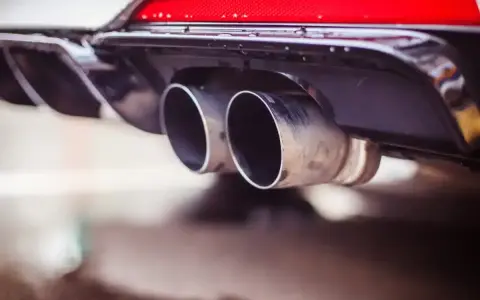 Double sortie d'échappement d'une voiture. La question "peut-on rouler avec un catalyseur défectueux" se pose face à ces gaz d'échappement.