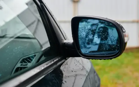 Rétroviseur droit obligatoire depuis quand ? Ce miroir de voiture, couvert de gouttes de pluie, reflète un ciel gris.