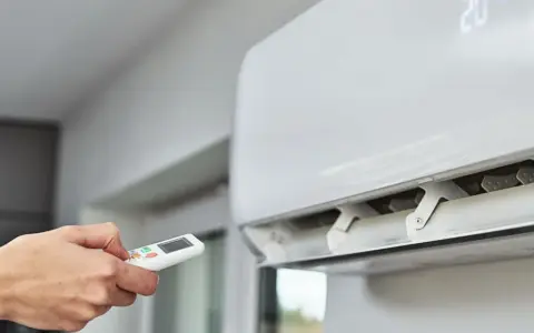 Main tenant utilise la télécommande pour régler la climatisation. Un problème climatisation voiture ? Ici, c'est pour une maison.
