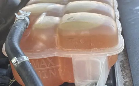 Le réservoir de liquide de refroidissement est plein, indiquant trop de liquide de refroidissement. Les marques MAX et MIN sont visibles.