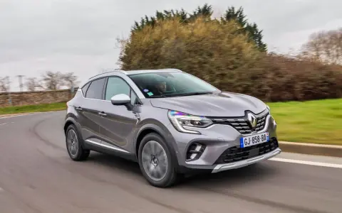 Une Renault Captur 2 grise roule sur une route sinueuse, prête pour son programme d'entretien.