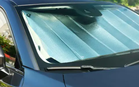 Pare-soleil argenté installé sur un pare-brise de voiture. Facile à mettre, il protège de la chaleur.