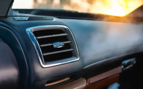 Le tableau de bord d'une voiture moderne, avec une grille de ventilation chromée. L'AC, ou climatisation, permet de réguler la température intérieure.