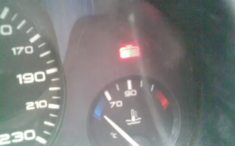 Tableau de bord d'une Peugeot 406 : voyant liquide de refroidissement allumé, aiguille de température à 70°C.
