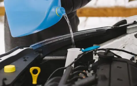 Personne verse du liquide dans le réservoir pour fabriquer lave glace. Le liquide coule d'une grande bouteille bleue vers le compartiment moteur.
