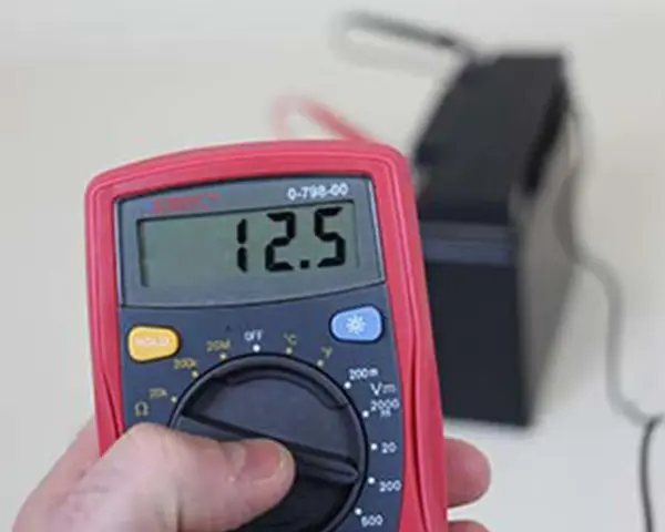 Multimètre affichant 12.5V, indiquant une batterie déchargée ou morte.