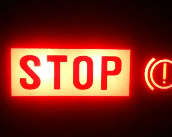 Voyant STOP et symbole de frein à main allumés en rouge. Vérifiez le niveau du liquide de frein.