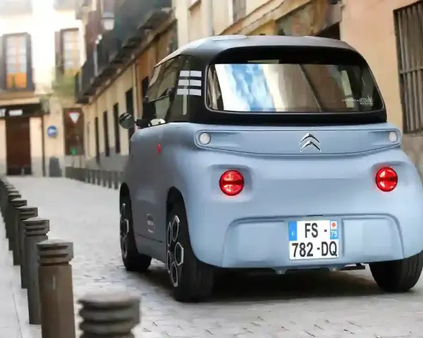 Citroën Ami bleu pastel dans une ruelle pavée. Peut-on acheter un véhicule sans contrôle technique ? Ce petit véhicule électrique est prêt à rouler.